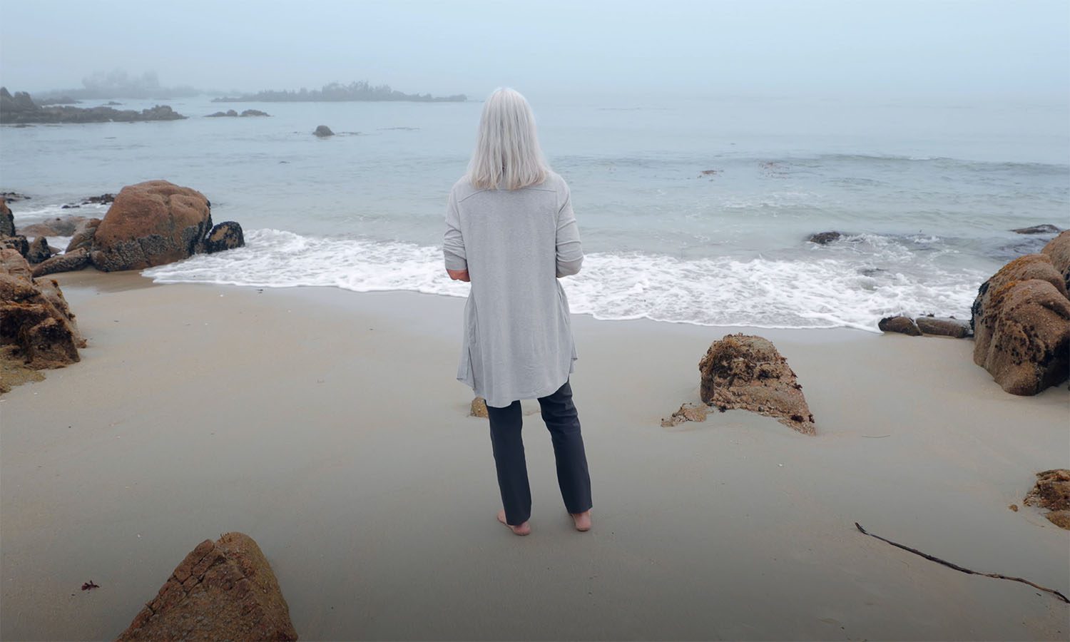 Julie Packard on a beach, staring out into the water